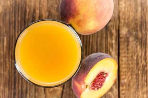 Portion of Peach juice (fresh made) on an old wooden table (close-up shot)