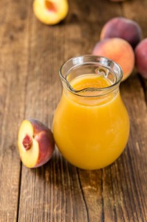 Portion of Peach juice (fresh made) on an old wooden table (close-up shot)