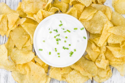 Fresh made Potato Chips with Sour Cream taste on a vintage background (close-up shot)