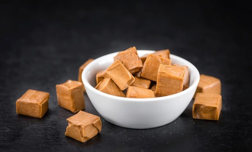 Portion of Caramel candy as detailed close up shot on a slate slab (selective focus)