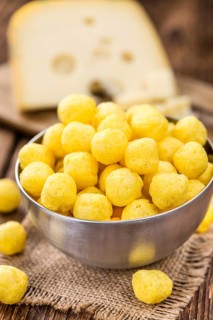 Cheese Balls (fried) as high detailed close-up shot on a vintage wooden table (selective focus)