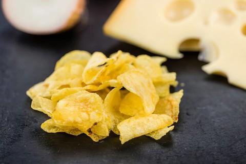 Some Potato Chips (Cheese and Onoion taste) on a slate slab (close-up shot, selective focus)
