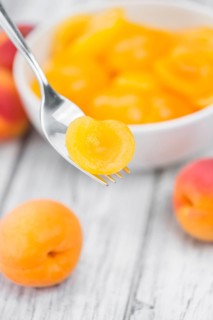 Canned Apricots on an old wooden table as detailed close-up shot (selective focus)