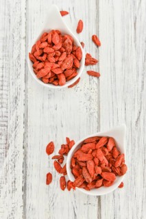 Dried Goji Berries as high detailed close-up shot on a vintage wooden table (selective focus)