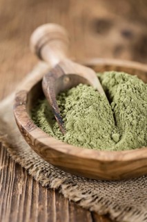 Portion of Stevia leaf powder (detailed close-up shot) on rustic wooden background
