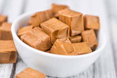 Caramel pieces as high detailed close-up shot on a vintage wooden table (selective focus)