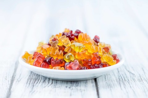 Bowl with Gummy Candy (selective focus) on wooden background