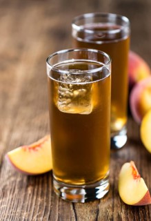 Fresh made peach ice tea (selective focus) on an old wooden table (close-up shot)