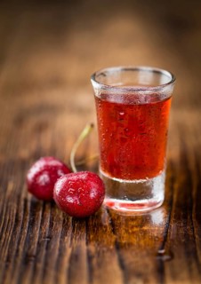 Homemade Cherry Liqueur on an wooden table as detailed close-up shot, selective focus
