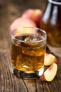 Ice Tea (Peach) on an old wooden table (selective focus, close-up shot)