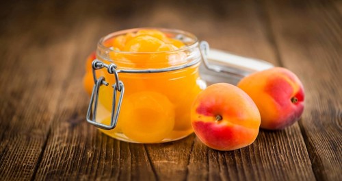 Canned Apricots on an old wooden table as detailed close-up shot (selective focus)