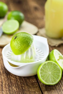 Fresh Lime Juice as high detailed close-up shot on a vintage wooden table (selective focus)