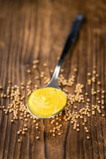Fresh made Mustard on a vintage background (close-up shot)