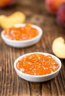 Peach Jam (selective focus) on an old wooden table (close-up shot)