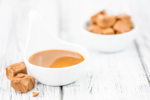 Caramel Sauce on an old wooden table as detailed close-up shot (selective focus)