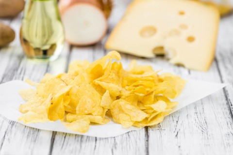Cheese and Onion Potato Chips on a vintage background as detailed close-up shot (selective focus)