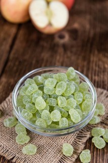Wooden table with sour gummy candy (apple taste) as detailed close-up shot