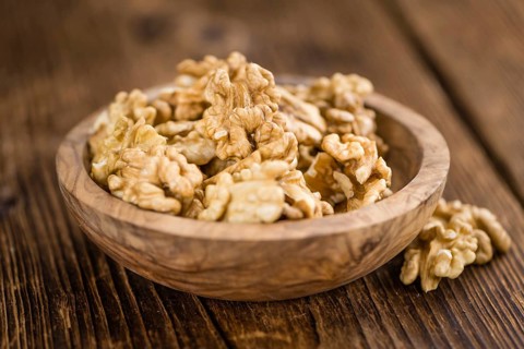 Cracked Walnuts as high detailed close-up shot on a vintage wooden table (selective focus)