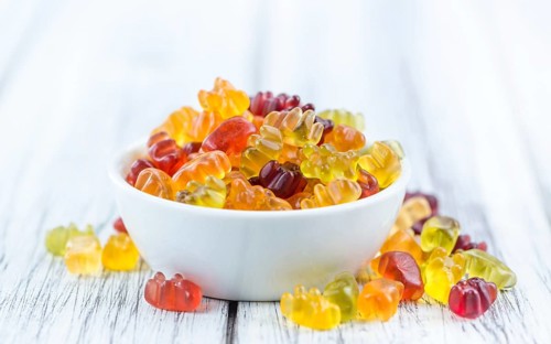 Bowl with Gummy Candy (selective focus) on wooden background