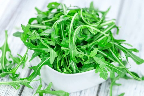 Wooden table with fresh Arugula as detailed close-up shot (selective focus)