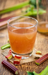 Old wooden table with fresh made Rhubarb Juice as detailed close up shot (selective focus)