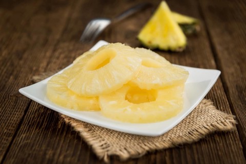 Preserved Pineapple Rings as high detailed close-up shot on a vintage wooden table, selective focus