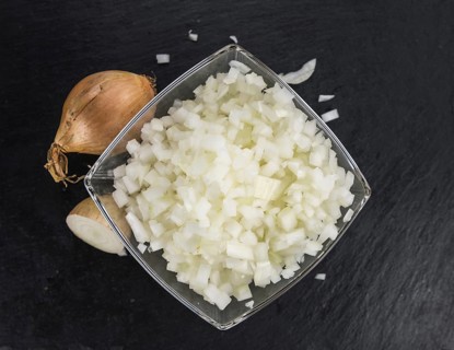 Portion of Chopped white onions as detailed close up shot on a slate slab, selective focus