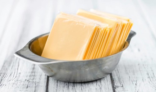 Cheese (sliced) on an old wooden table as detailed close-up shot (selective focus)