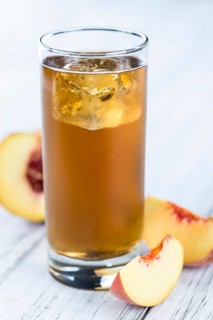 Ice Tea (Peach) on an old wooden table (selective focus, close-up shot)