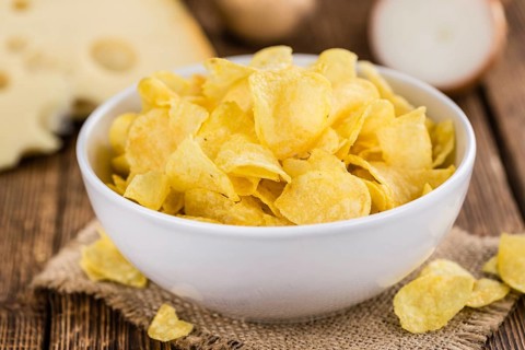 Homemade Cheese and Onion Potato Chips on vintage background (selective focus, close-up shot)