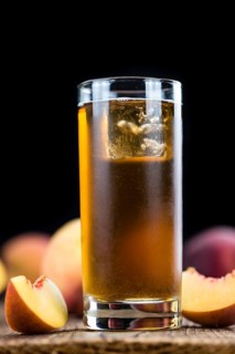 Peach ice tea (selective focus) on an old wooden table (close-up shot)