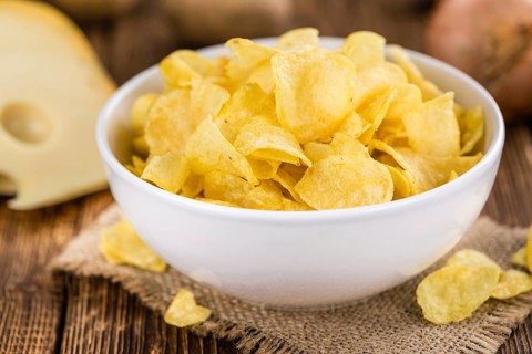 Cheese and Onion Potato Chips on an old wooden table as detailed close-up shot (selective focus)