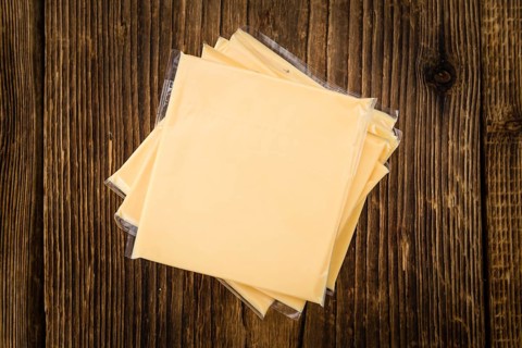 Cheese (sliced) on an old wooden table as detailed close-up shot (selective focus)