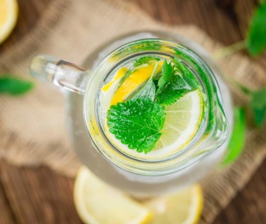 Lemonade (with Balm) as high detailed close-up shot on a vintage wooden table (selective focus)