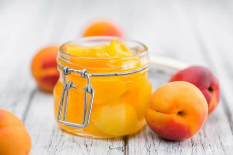 Canned Apricots on an old wooden table as detailed close-up shot (selective focus)