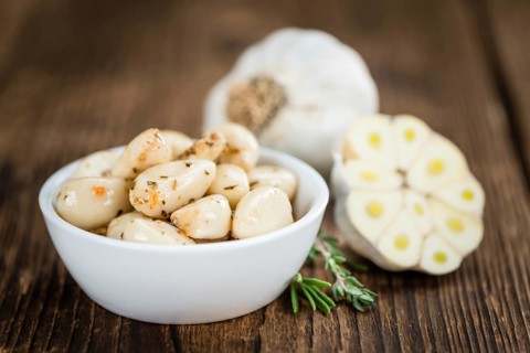Marinated Garlic on an old wooden table as detailed close-up shot (selective focus)