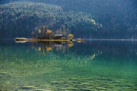 Island with wooden hut in autumn in Lake Eibsee lake in the Bavarian Alps