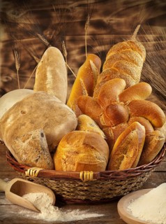 Wicker basket with different types of bread on wooden table