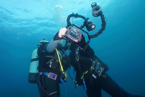 Two divers take a photo, selfie, underwater with a camera. Dive site Marine reserve Cap de Creus,