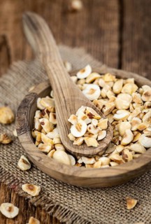 Portion of freshly chopped Hazelnuts on an old wooden table as detailed close up shot (selective