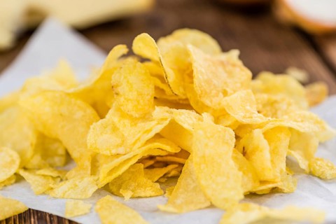 Homemade Cheese and Onion Potato Chips on vintage background (selective focus, close-up shot)