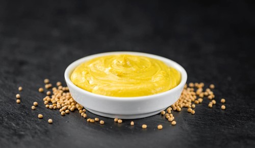 Fresh made Mustard on a vintage background (close-up shot)