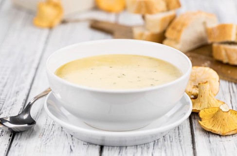 Chanterelle Soup as high detailed close-up shot on a vintage wooden table, selective focus