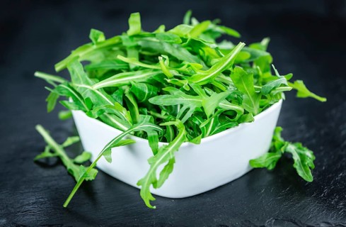 Fresh Arugula (selective focus) as detailed close-up shot on vintage background