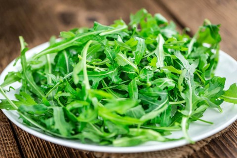 Fresh Arugula on an old wooden table as detailed close-up shot