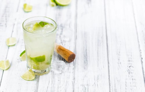 Caipirinha made with fresh limes, ice and sugar as close-up shot