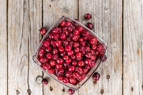 Old wooden table with fresh Preserved Cranberries (close-up shot, selective focus)
