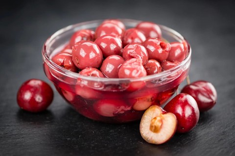 Portion of Preserved Cherries as detailed close up shot on a slate slab, selective focus