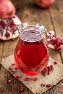 Pomegranate juice as high detailed close-up shot on a vintage wooden table (selective focus)