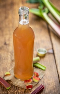 Old wooden table with fresh made Rhubarb Juice as detailed close up shot (selective focus)